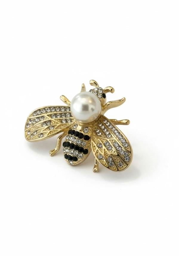 Gold bee-shaped brooch with a pearl body on a white background