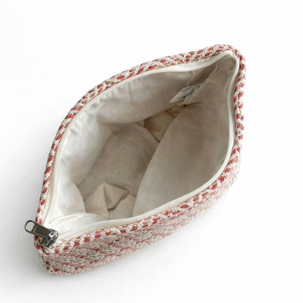 Coral woven toiletry bag open to show beige fabric lining and zipper