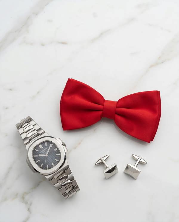 Red bow tie with silver watch and cufflinks on a marble surface
