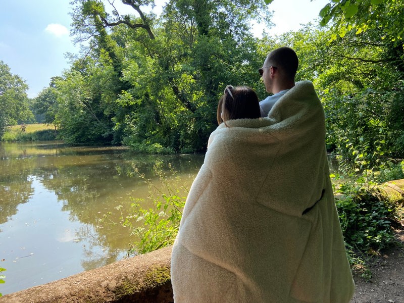 A young couple, huddled together with a vivid spruce outdoor sherpa fleece lined Blanko blanket outdoors. imageset:Vivid Spruce