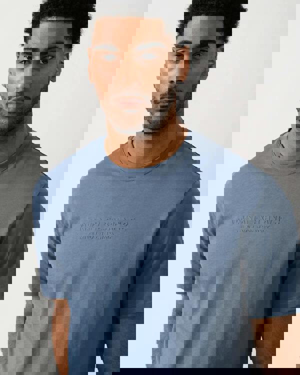 detail view of a Model wearing an Armani Exchange Mens T-Shirt with Tonal Milano/New York Logo in China Blue U9302