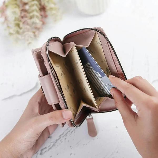 Person holding a pink wallet with cards on a light background