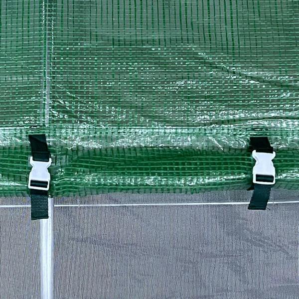 Green mesh greenhouse cover secured to galvanized frame with white clamps and straps