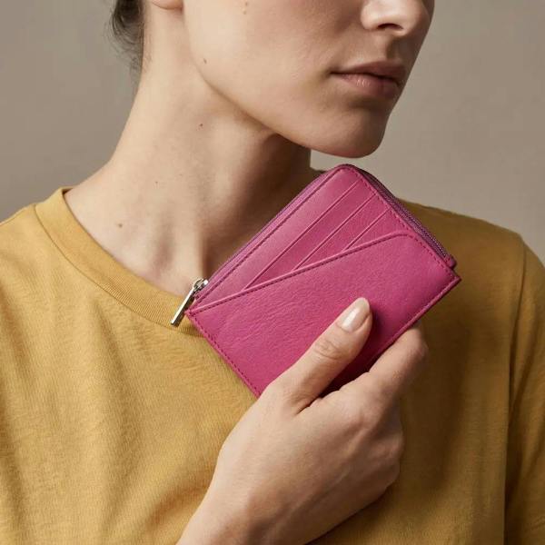 Person holding a pink wallet against a neutral background