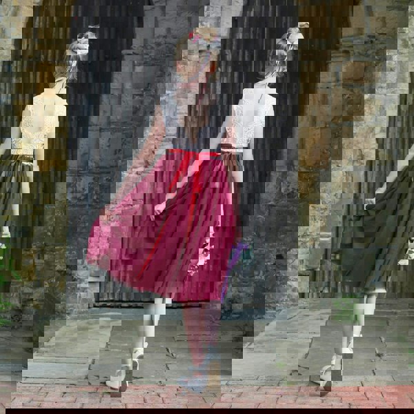 Girl in a red and white dress standing in front of a stone wall.