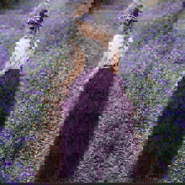 Young girl in a purple dress standing in a field of purple flowers.