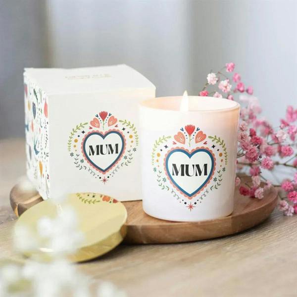 White 'MUM' heart candle with lid, beside matching gift box on a wooden tray.