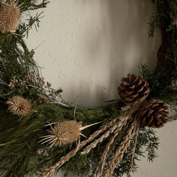 Detailed view of the Elowen wreath showing pinecones, dried thistles, and hand-woven panchu sticks.