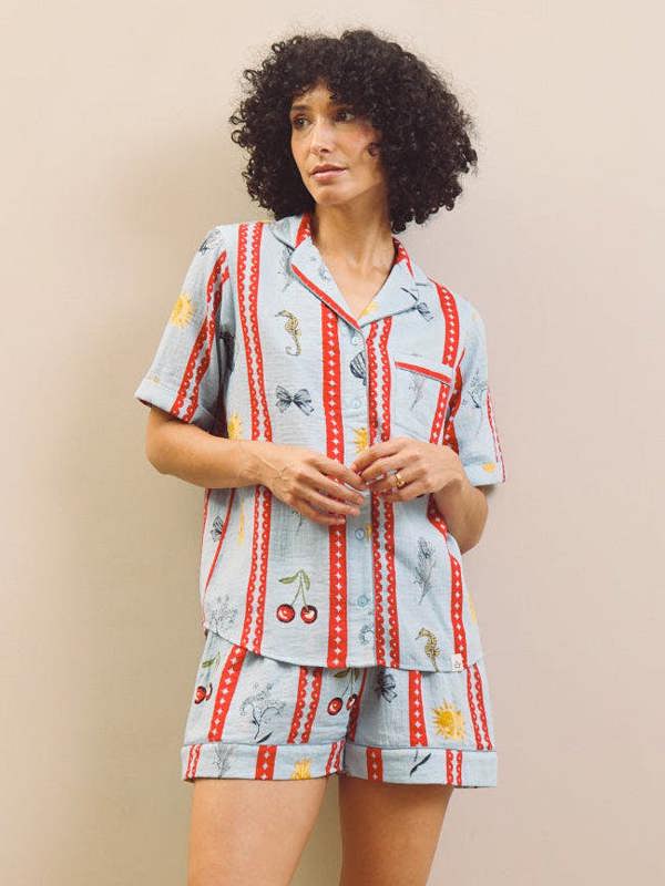 Woman wearing a patterned pajama set against a plain wall.