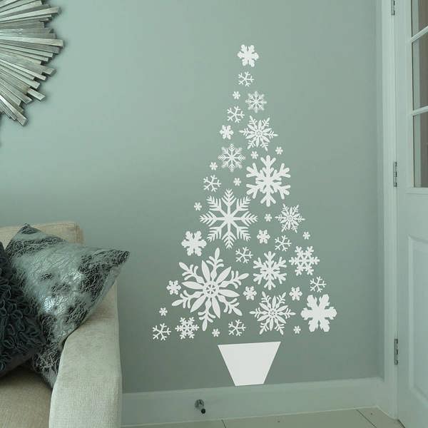 A large white vinyl snowflake Christmas tree wall sticker decal styled on a duck egg blue living room wall next to a beige sofa.