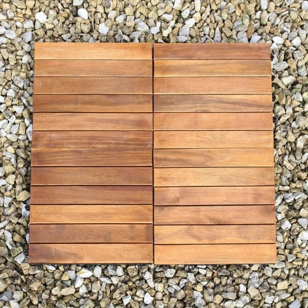 Natural wooden decking tiles with a smooth finish, arranged in a grid pattern, set against a backdrop of small stones