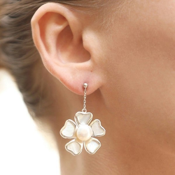 A close up of an ear with a silver floral earrings.