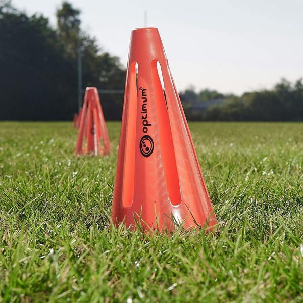Red Optimum training marker cone with black logo standing on a grass pitch outdoors - Optimum