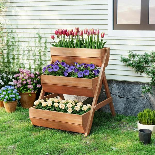 Brown 3-tier raised wooden planter box on grass with tulips and purple flowers