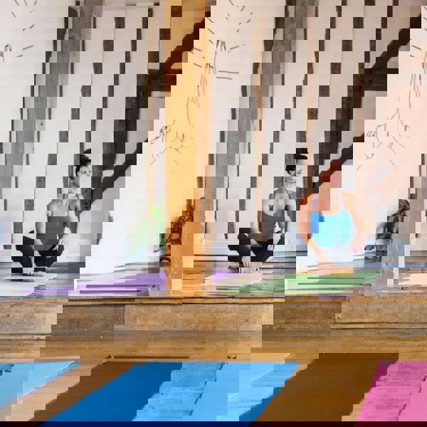 Woman sitting cross legged on green Fitness Mad 4mm Warrior II Yoga Mat - Gym Class