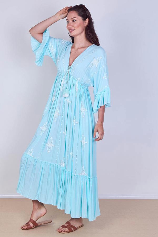 Woman wearing a light blue dress with floral patterns against a plain background