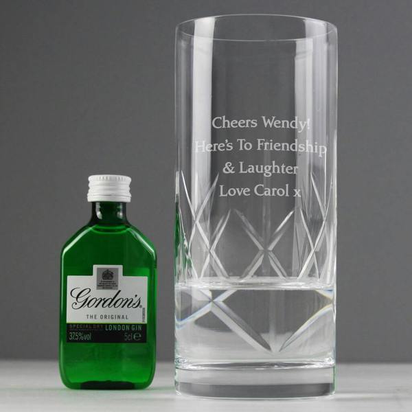 A custom-engraved cut crystal hi-ball glass reading Cheers Wendy beside a green miniature bottle of Gordon's Gin.