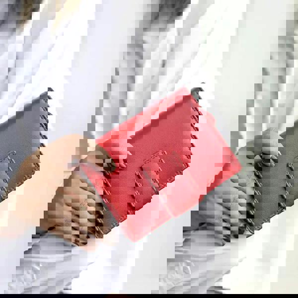 Person holding soft red leather trifold purse with secure tab fastening