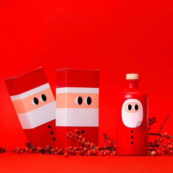 Studio display of the 500ml Santa edition extra virgin olive oil bottle surrounded by custom Santa packaging boxes and red winter berries.
