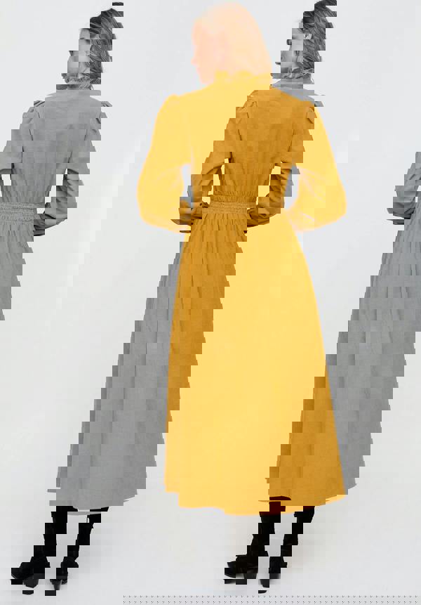 Woman wearing a mustard yellow dress on a white background