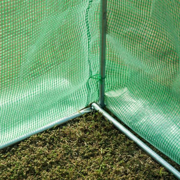 Inside corner of green polytunnel greenhouse with metal support pole and floor mesh base