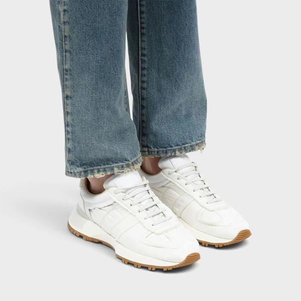 Supplied Fashion Maison Margiela 50-50 white leather sneakers with split-sole design worn with blue denim jeans.