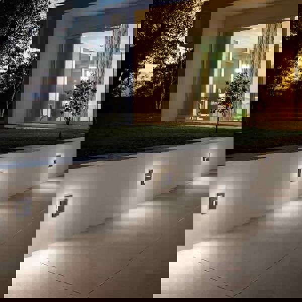 black flush outdoor wall light mounted in a row at low level along an exterior wall 