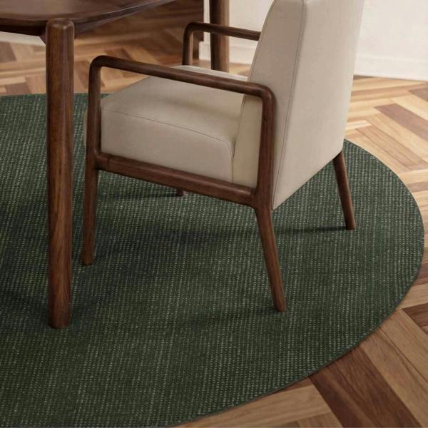 Chair with wooden frame and beige cushion on a green round rug in a room with wooden flooring.