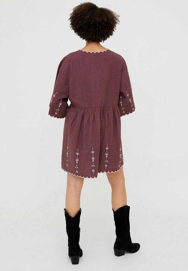 Person wearing a burgundy dress with lace details on a white background