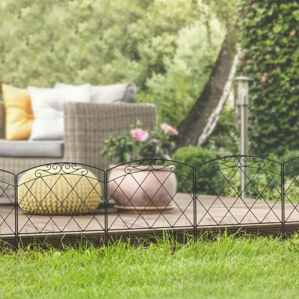Black metal garden fence line with arched diamond lattice and decorative swirl tops