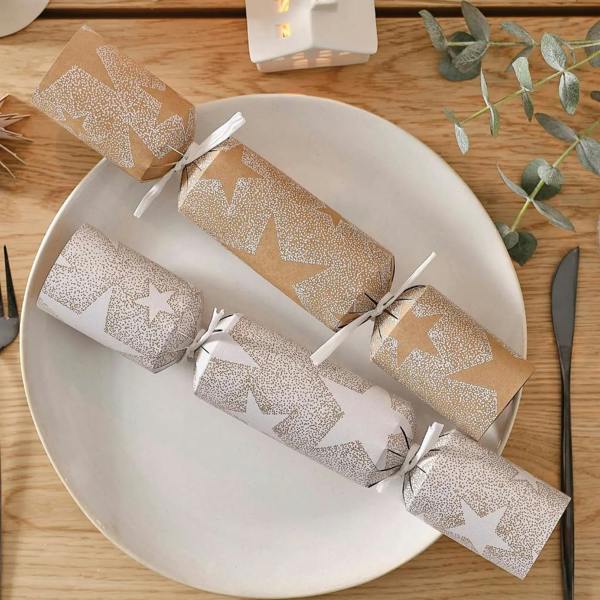 Two luxury recyclable Christmas crackers with gold and white star patterns on a white dinner plate.