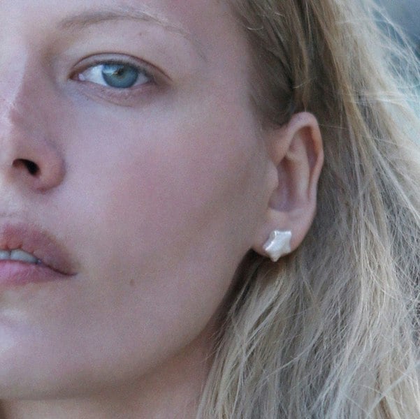Close up of a model's face and ear with star-shaped pearl stud.