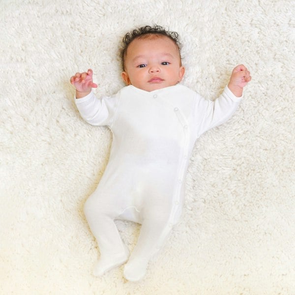 Newborn baby wearing Prima Cotton’s Organic Baby Sleepsuit for Sensitive Skin made from 100% GOTS-certified organic Egyptian cotton with a side snap fastening.