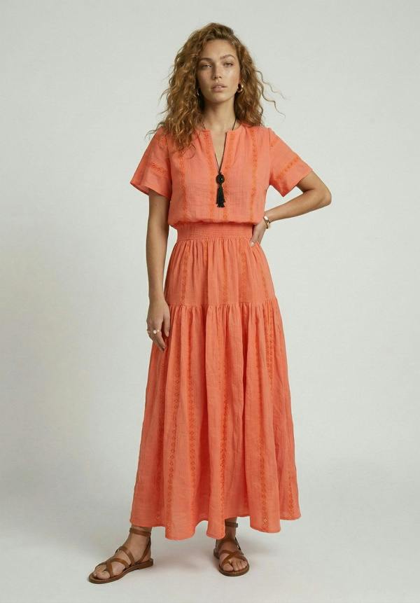 Woman wearing an orange dress with a plain background