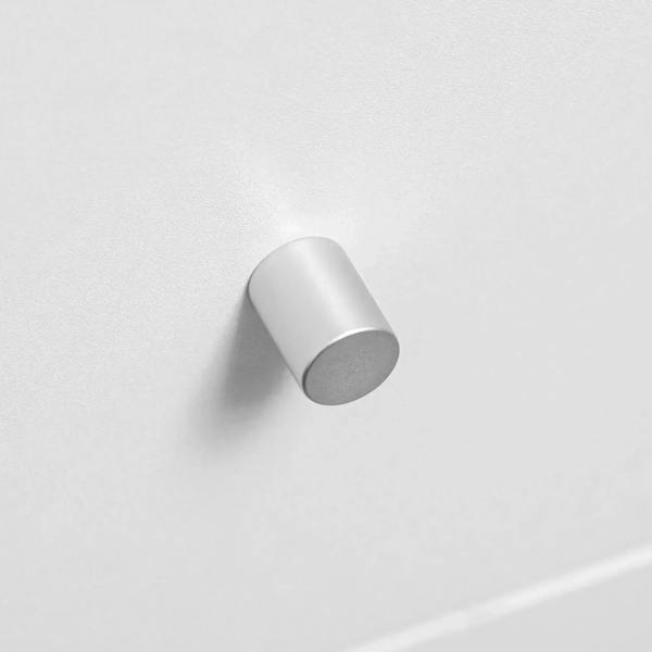 Silver cylindrical cabinet knob on white drawer front