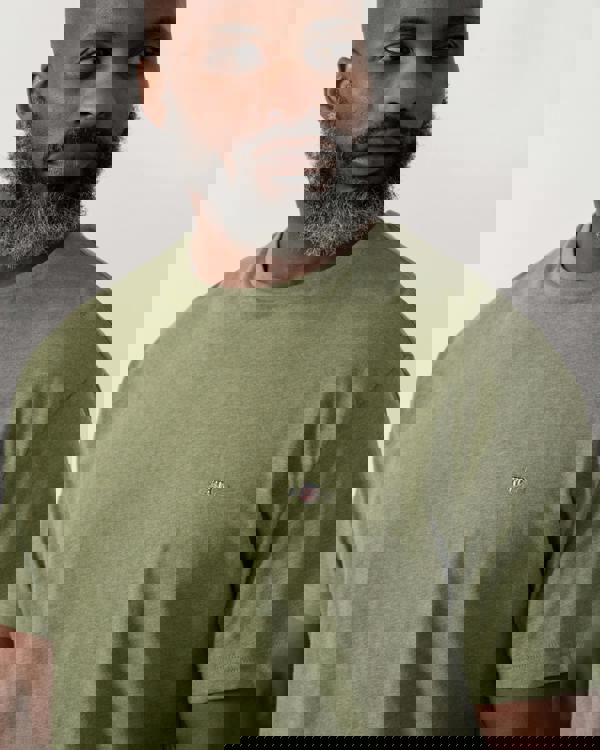 detail shot a a model wearing a GANT Mens Regular Fit Short Sleeve Shield Logo T-Shirt in Dark Cactus Melange