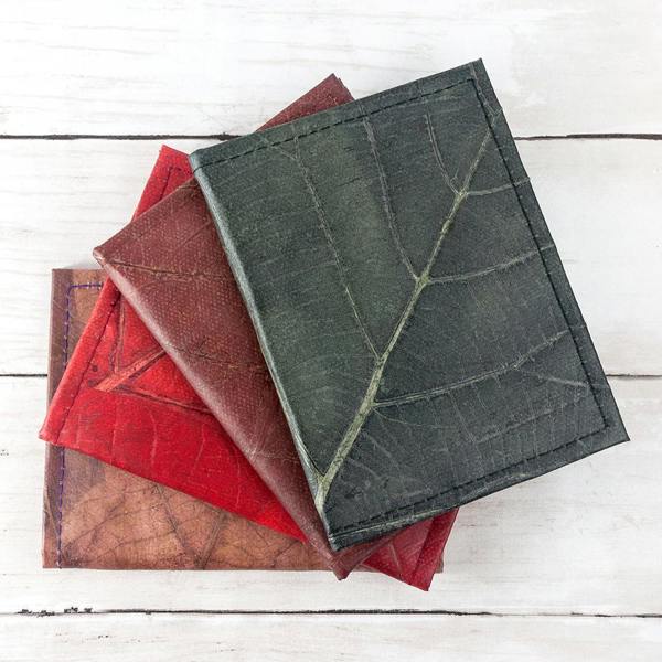 Sustainably produced leaf leather passport covers in green, red, and brown, handcrafted from naturally dyed fallen leaves to showcase unique, one-of-a-kind textures and intricate leaf veins.