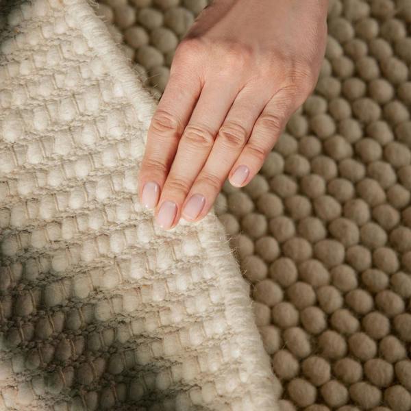 Hand touching a textured beige fabric surface