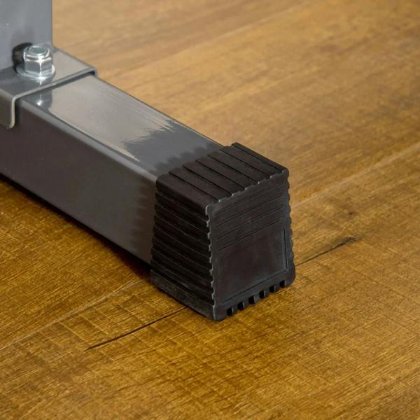 Black rubber base feet for the weight bench frame on a wooden floor