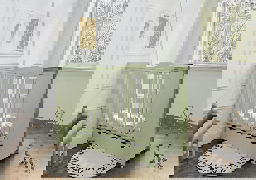 A stylish pistachio green baby cot in a modern nursery. The cot features an adjustable base and sleek design, paired with a breathable bamboo mattress – perfect for small, contemporary baby rooms. Converts to junior/toddler bed.