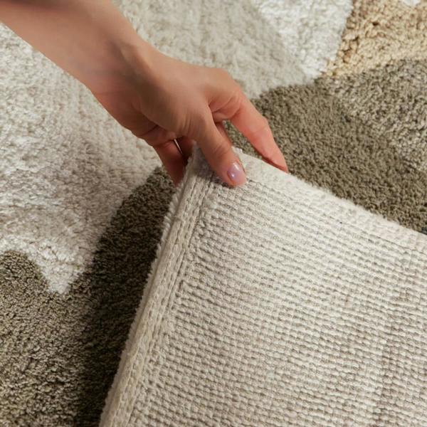 Hand touching a textured beige carpet