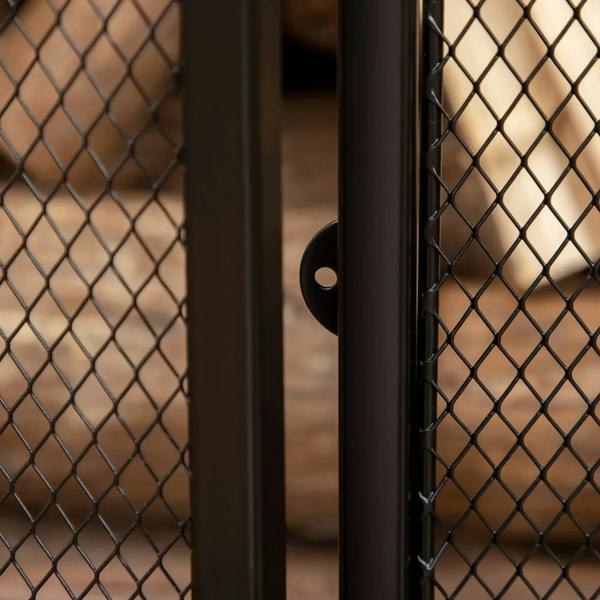 Black metal mesh fireplace screen close-up with door edge and latch hardware