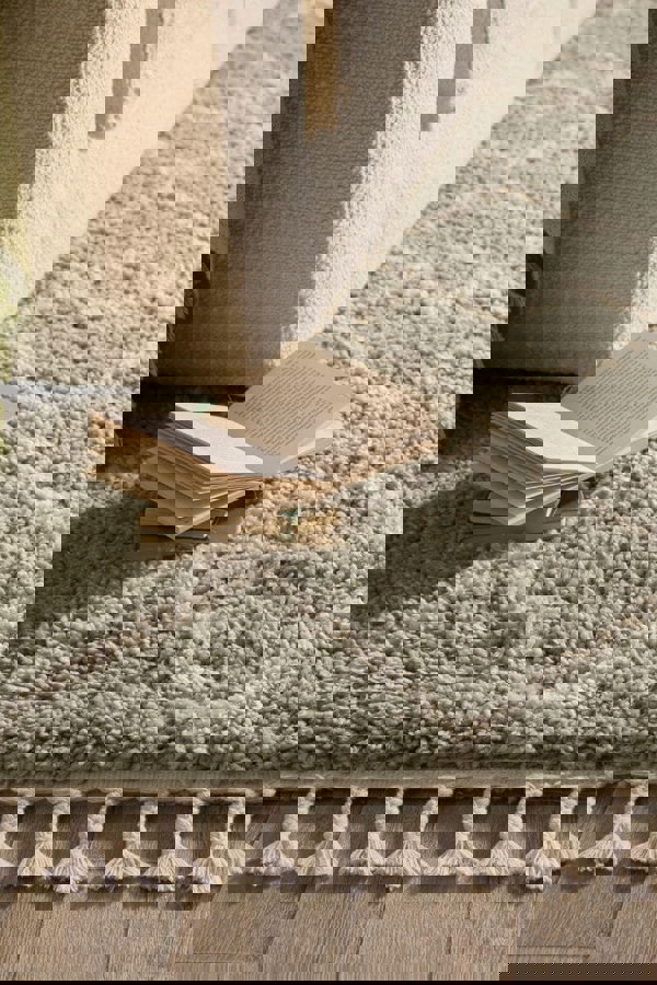 Moroccan-style rug in Eucalyptus Green with intricate design, paired with an open book on the floor.