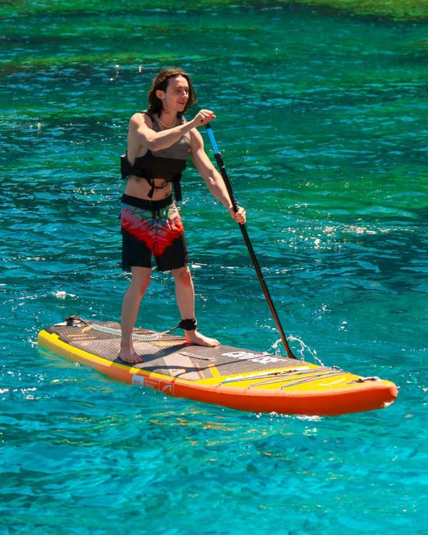 Someone on a Bluefin Cruise 10'8 Orange Sunset paddle board sup in clear ocean water 