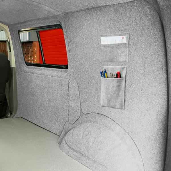 Silver grey storage pouches mounted on a textured wall, featuring pockets for organizing pens and tools in a vehicle interior