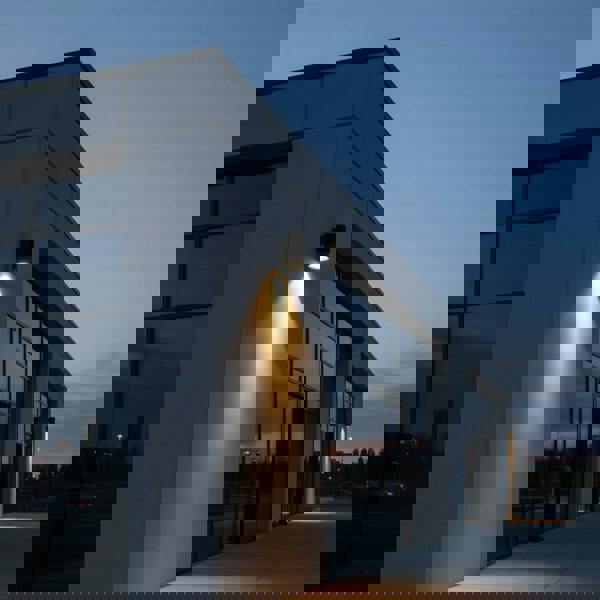 black large outdoor wall downlight mounted on the exterior of a large building shining light down the wall 