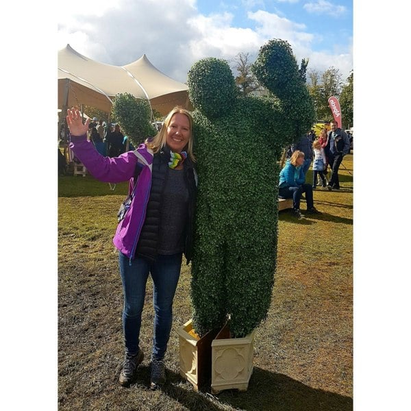 Customer wearing her world champion rainbow Ruffnek neck gaiter as a supporters scarf whilst watching the UCI cycle race and bumped into a giant hedge man! World Cycling Champion Multi Scarf – a versatile, breathable accessory for UK cyclists. Perfect for rides in all weather. #CyclingGear #UKCyclingStyle #CyclingGear, #BikeAccessories, #MultiScarf