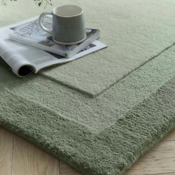 Green rug with a gray mug and newspaper on top