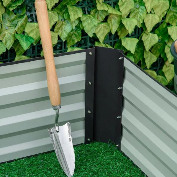 Corner of metal raised garden bed planter box with gardening shovel and soil-filled view