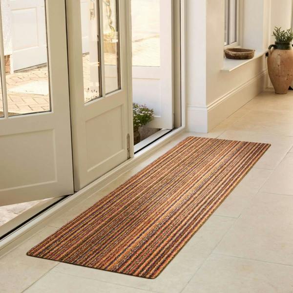 Striped doormat on a tiled floor in front of glass doors.